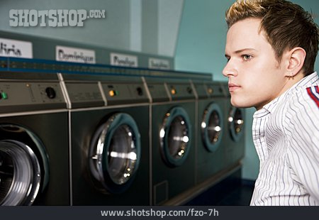 
                Junger Mann, Warten, Waschmaschine, Waschsalon                   