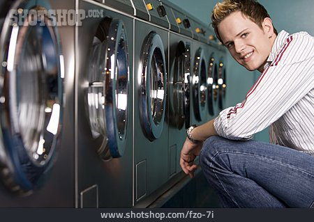 
                Junger Mann, Waschmaschine, Wartezeit, Waschsalon                   