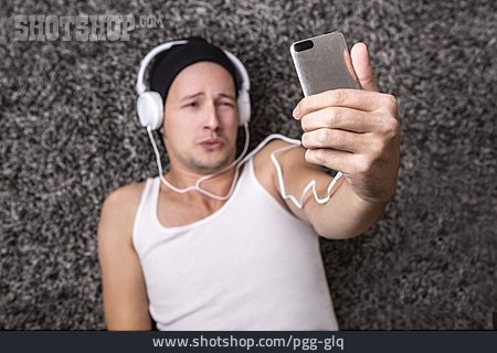 
                Junger Mann, Mobiltelefon, Musik Hören                   