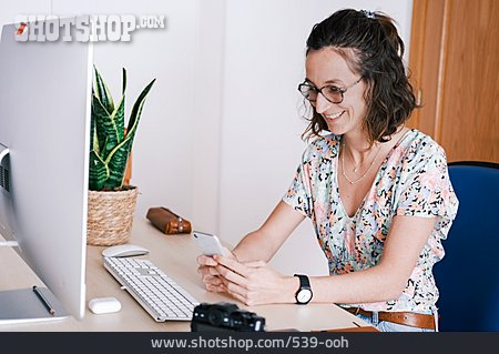 
                Frau, Lächeln, Lesen, Smartphone, Computerarbeitsplatz                   